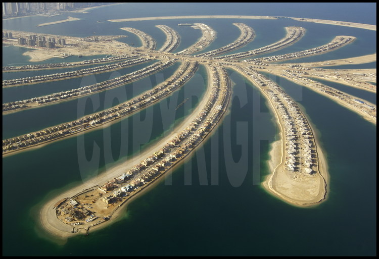June 2006. Off-shore building site for “Palm Jumeirah”. With its 3840 km2, Dubai has only a short coast.  For this reason, in 2001 this little emirate began the tremendous project of increasing its coastline by building the world’s biggest artificial islands.  Unique in its category, “Palm Jumeirah” is a tourist complex on the ocean in the shape of a trunk with 17 palm leaves surrounded by an 11-km-long dyke.   60 kilometres of beach were created by relocating over 100 million m3 of sand and rocks to this 5km-diameter complex.  Potentially finished at the end of 2006, “Palm Jumeirah” will house several dozens of hotels, thousands of private houses and apartments as well as marinas, restaurants, water parks, shopping malls, sports fields, mineral springs, cinemas, etc.  A 300-meter bridge will join the “trunk” to the continent.  A monorail will lead to the “Atlantis Resort”, at the heart of the complex, made up of a hotel with over 1000 rooms and an aquatic park.