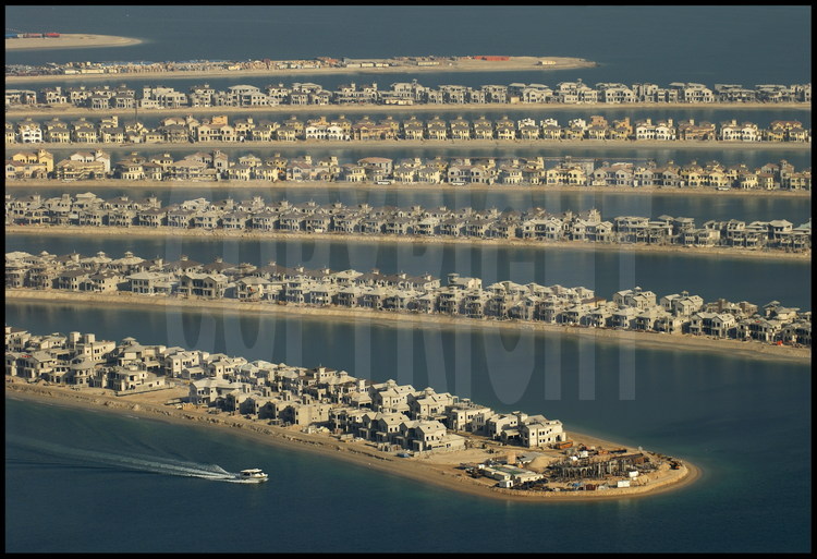 June 2006. Off-shore building site for “Palm Jumeirah”. With its 3840 km2, Dubai has only a short coast.  For this reason, in 2001 this little emirate began the tremendous project of increasing its coastline by building the world’s biggest artificial islands.  Unique in its category, “Palm Jumeirah” is a tourist complex on the ocean in the shape of a trunk with 17 palm leaves surrounded by an 11-km-long dyke.   60 kilometres of beach were created by relocating over 100 million m3 of sand and rocks to this 5km-diameter complex.  Potentially finished at the end of 2006, “Palm Jumeirah” will house several dozens of hotels, thousands of private houses and apartments as well as marinas, restaurants, water parks, shopping malls, sports fields, mineral springs, cinemas, etc.  A 300-meter bridge will join the “trunk” to the continent.  A monorail will lead to the “Atlantis Resort”, at the heart of the complex, made up of a hotel with over 1000 rooms and an aquatic park.