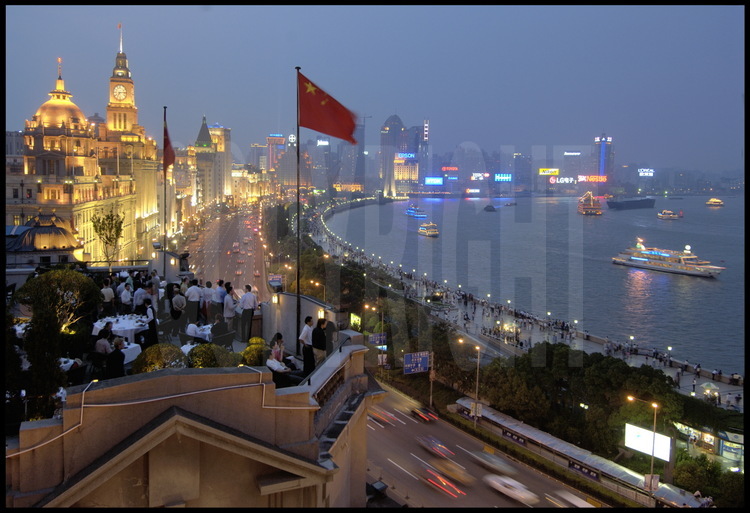 In downtown Shanghai, the Bund embankments and barges along Huang pu river in 2005. On first ground, a terrace of one the new switched-on restaurant in town.