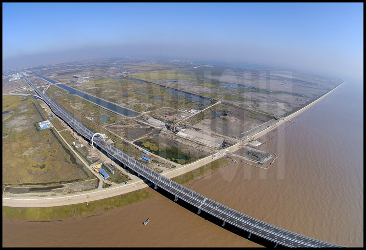 Départ du pont de Donghai -côté Shanghai- non loin de la ville côtière de Luchao. Sur l’ensemble de cette zone, où n’existait qu’un modeste village de pêcheurs, sera implanté un complexe logistique, industriel et touristique prévu pour héberger 300000 habitants en 2010. En haut à gauche, la station de péage: le passage coûte 20 yuans (2,2 €) pour les voitures et 50 yuans (5,5 €) pour les camions. En haut à droite, le bassin central de la future marina de Luchao, qui sera terminée en 2010.