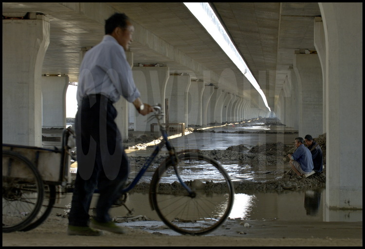 June 2005. Under Donghai bridge at kilometric point 1 -Shanghai side-. End of workday for this employee on bike. On background, elevation 1, five kilometers away.
