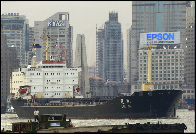 In Downtown Shanghai, an oil tanker cruising on Huang Pu river, as easy as a simple barge. On background, offices  towers of Puxi (meanings 