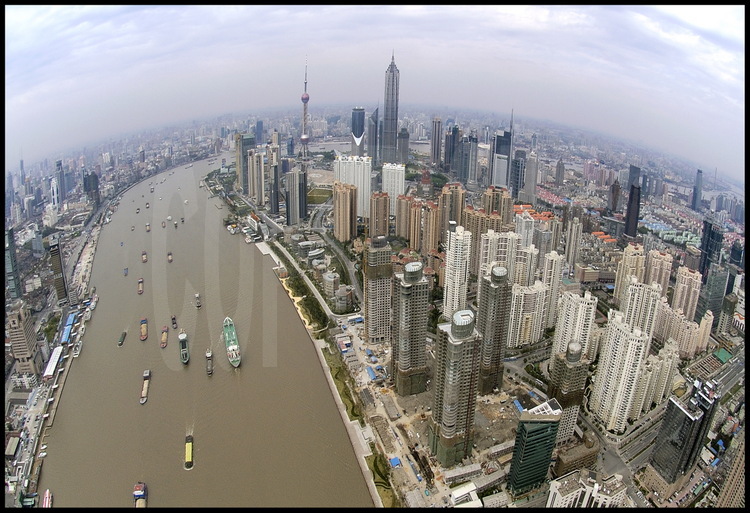 Downtown Shanghai from top of Huang Pu river, with its huge trafic of vessels and barges of any tonnage. On right, the new city of Pudong (meanings 