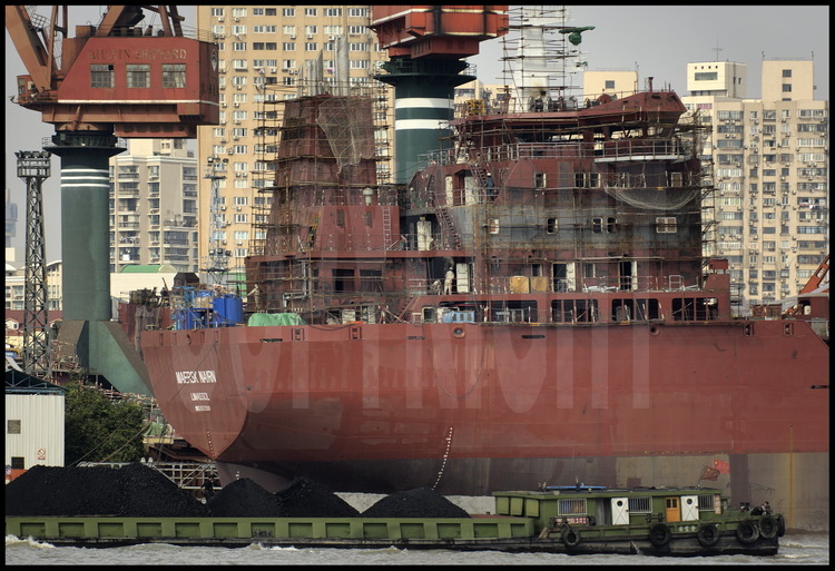 Révision générale au chantier naval de Qui Xin, situé sur la rive gauche de la Huang Pu river, pour le  «château» de ce porte-container chypriote de la compagnie Maersk basé à Limassol. En arrière plan, des tours d’habitation de Puxi (qui signifie « à l’est du Pu »).