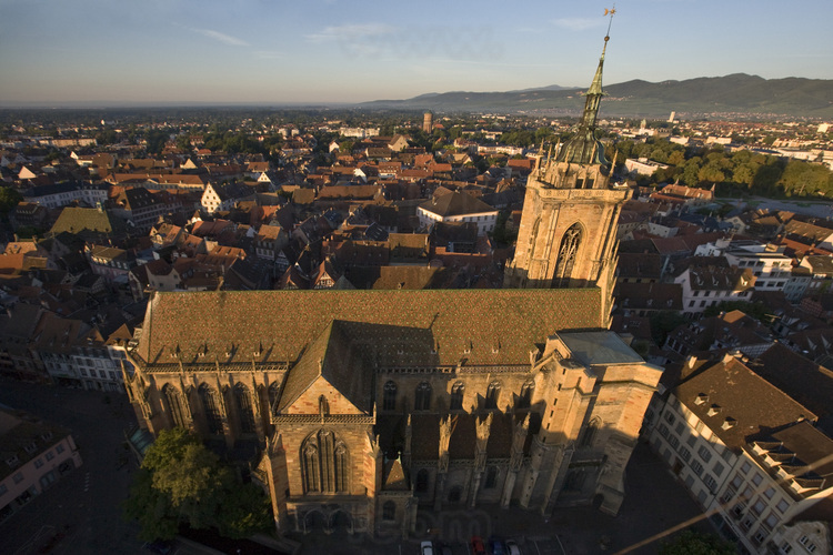 Centre historique. Collégiale Saint Martin. Construite de 1235 à 1365, la collégiale est une œuvre majeure de l'architecture gothique en Alsace. En arrière plan, la partie sud de la ville et la chaîne des Vosges. Altitude 70 m.
