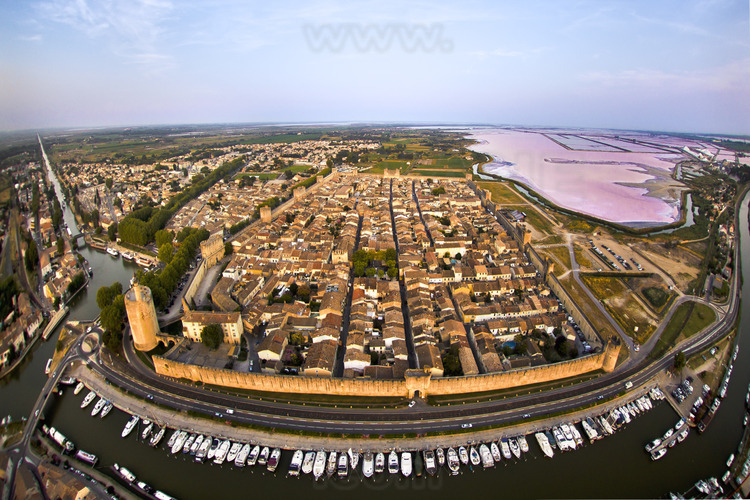 The walled city from the west. On the left, the tower of Constance. In the background on the right, the Salins du Midi (purplish in summer).