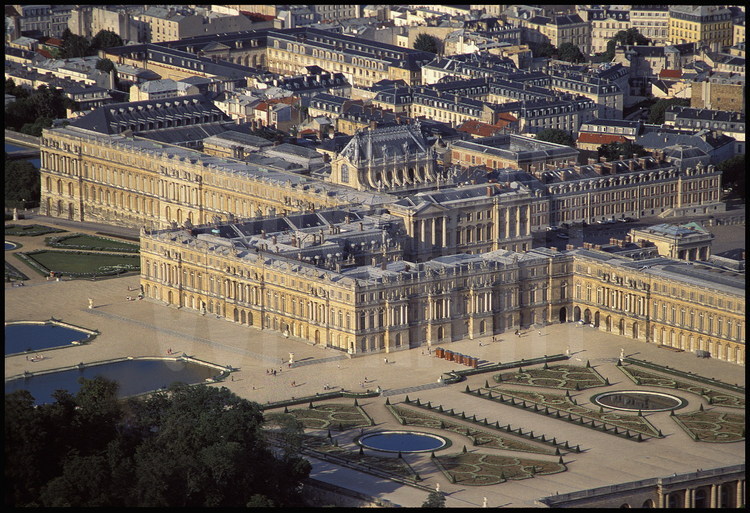 Vue générale du Château de Versailles. Au premier plan, le Parterre du Midi. Au second plan, de gauche à droite : les Parterres d’eau, le corps central et l’aile du Midi. En arrière plan, l’Aile du Nord et le centre ville historique.