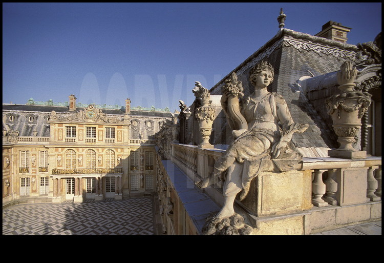Vue générale de la Cour de Marbre depuis l’aile Gabriel. Dix-huit statues représentant  les Vertus royales et les Parties du Monde ornent la balustrade. Dans l’angle, la statue de la Paix.