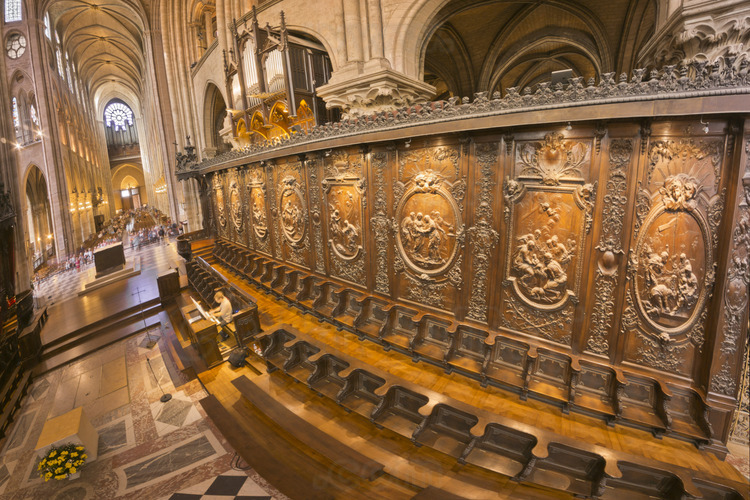 The choir stalls viewed from the apse. They were made under Louis XIV, during the redevelopment of the choir (which featured a jube). Panels that adorn the stalls depict scenes from the life of the Virgin. This space, inaccessible to the public, is the place of the celebration of the offices. In the background, the central transept and the nave.