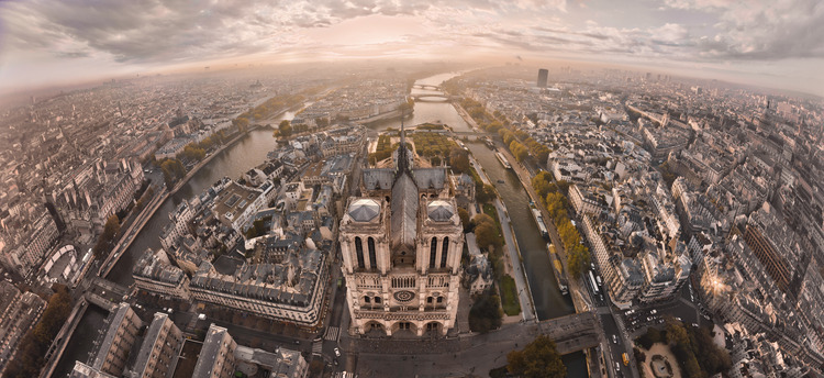 The west facade of Notre Dame de Paris at sunrise. On the court, the zero kilometer point, which marks the intersection of the roads of France. In the foreground, l. to r., the place de l'Hotel de Ville, the north arm of the Seine and the bridge of Arcola, Arcola Street, the square of Notre Dame, the southern arm of the Seine and the Pont au Double, the Lagrange street and the Square René Viviani. In the second ground, l. to r., City Hall, the National School of the Judiciary, Square Jean XXIII, the bridge of the Archdiocese, the Quai de Montebello and the Latin Quarter. In the background of l. to r., the Quai de l'Hotel de Ville, the church of Saint Gervais, Saint Louis island, the bridges of Tournelle and Sully, the Jussieu university and École Polytechnique. Altitude 140 meters.