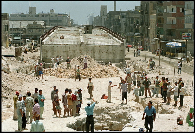 General view of the Necropolis digging site.  In the background, the overpass whose construction led to the ancient site’s discovery.  Today, the overpass threatens its preservation.  For the duration of the digs, two hundred workers are on site daily with the archeologists.  On the bottom right, the ancient entry to tomb VIII.