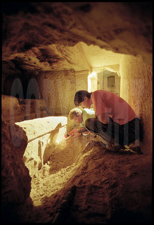 Au fond de la tombe XIII, découverte par le petit Balah, les archéologues Frédéric Bernard (à gauche) et Hélène Silhouette (à droite) observent un sarcophage sculpté de l'époque ptolémaïque appartenant à une riche famille, avec guirlandes, et anneaux rehaussés de peinture rouge.