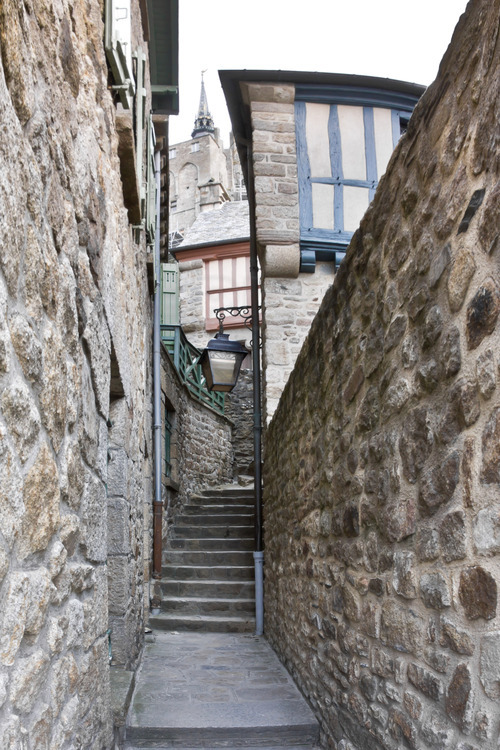 Rue en escalier du village du Mont Saint Michel. En arrière plan, la flèche de l'église abbatiale.