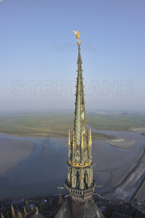 Surmontée de la statue de l'archange Saint Michel, la flèche de l'église abbatiale du Mont Saint Michel vu depuis l'est.
