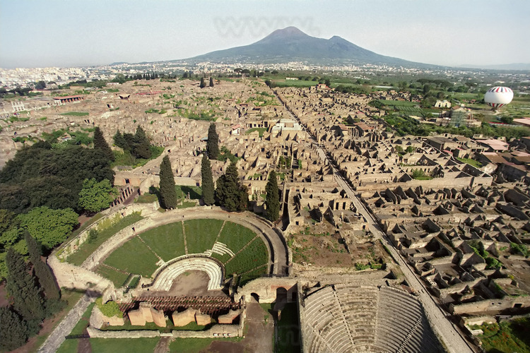 Vue aérienne de Pompéi depuis le Sud. Au premier plan, le théâtre et l'odéon. A droite, la via Stabbiana, qui traverse la cité antique du nord au sud. En arrière plan, le Vésuve.