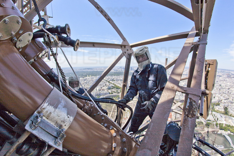 A 300 mètres d’altitude, juste à la base de l’antenne blanche de la tour Eiffel, les techniciens de TDF effectuent les travaux de reconfiguration du système antennaire, nécessaires pour le passage au tout-numérique. Effectués de jour (donc sans coupure d’émission) , ces travaux nécessitent d’être équipés de vêtement de protection pour éviter tout risque d’irradiation.