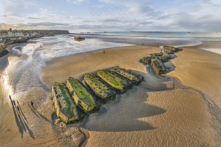 Normandie - Calvados (14) - Arromanches les Bains : Site 4 : Gold Beach - Vestiges du port artificiel allié B (pour British) à Arromanches les Bains. Le port Mulberry fut construit pour permettre l'approvisionnement des armées alliées dans les jours qui suivirent le débarquement de Normandie. En fait, deux ports furent assembles au large des plages du Calvados, mais seul celui d'Arromanches sera opérationnel, le second devant Omaha Beach étant détruit par une tempête le 19 juin 1944. La construction de ce port évitait aux Alliés de devoir prendre directement un port en eau profonde. Le port Mulberry était constitué de différents grands éléments préfabriqués en Angleterre, acheminés et assemblés sur la cote normande. Ce port artificiel a souvent été mis en avant comme ayant permis la réussite de la bataille de Normandie et présenté comme un exemple de génie logistique et militaire. // France - Normandy - Calvados (14) - Arromanches les Bains: Site 4: Gold Beach - Remains of the artificial port Allied B (for British) in Arromanches les Bains. Mulberry Port was built to supply the Allied armies in the days following the Normandy landings. In fact, two ports were assembled off the beaches of Calvados, but only that of Arromanches was operational, the second in front of Omaha Beach being destroyed by a storm on June 19, 1944. The construction of this port avoided the Allies having to take direct a deep water port. Mulberry Port was made up of various large elements prefabricated in England, transported and assembled on the Normandy coast. This artificial port has often been highlighted as having enabled the success of the Battle of Normandy and presented as an example of logistical and military genius.