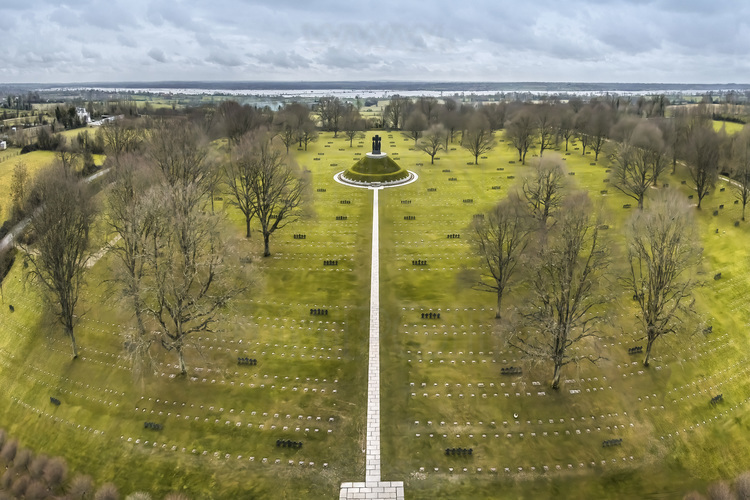 Normandie - Calvados (14) - La Cambe : Site 8 : Cimetiere allemand de La Cambe. Amenage et entretenu par l'association des familles allemandes, le site de La Cambe est le plus grand cimetiere militaire allemand de Normandie. 21 400 soldats allemands y sont enterres. Au centre, un tertre de six metres de haut, surmonte d'une croix de granit, est le tombeau commun de 296 combattants. Avec ses croix sombres et ses simples plaques carrees placees sur la pelouse qui indiquent les sepultures des soldats, le site offre un contraste saisissant avec le cimetiere des Allies. Le Jardin de la Paix est une plantation de 1220 erables, comme symboles vivants de la paix entre les nations. // France - Normandy - Calvados (14) - La Cambe: Site 8: La Cambe German Cemetery. Built and maintained by the association of German families, the La Cambe site is the largest German military cemetery in Normandy. 21,400 German soldiers are buried there. In the center, a mound six meters high, topped with a granite cross, is the common tomb of 296 combatants. With its dark crosses and simple square plaques placed on the lawn marking the soldiers' graves, the site offers a striking contrast to the Allied Cemetery. The Peace Garden is a plantation of 1220 maples, as living symbols of peace between nations.