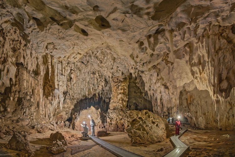 Auvergne Rhône Alpes - Ardèche (07) - Vallon Pont d'Arc - Visite exclusive de la grotte Chauvet 20 ans après sa découverte : Vue générale de la salle Brunel. A gauche, David Huguet et Jean Clottes observent le grand panneau des Point-Mains et le panneau de ponctuations rouges, à l'entrée de l'alcôve des Chevaux Jaunes. A droite Paulo Rodrigues, agent de la Conservation du Patrimoine pour la Grotte.