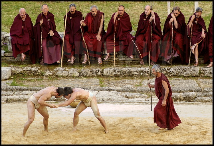 Combat between Greek wrestler Stefanos Tsanoulas (left) and Spanish wrestler Antonio Ledesma (right) under the watch of hellanodices (from left to right) Jean-Claude Perrin, Jose Luis Martinez Rodriguez, Harald Schmid, Giuseppe Gentile, Christos Kollias, Conrado Durantez, Andreas Bianchi, Philippe de Carbonnières; on the right Georges Ballery, former international French wrestler.