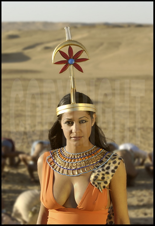 L’épouse du pharaon, vêtue de ses attributs royaux, l’aide dans sa quête. Métamorphosée en déesse Seshat, la divinité gardienne des mesures et des écrits, elle immortalise l’acte de fondation de la pyramide.