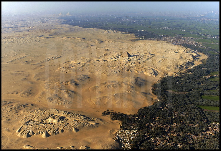 Vue aérienne de l’immense plateau funéraire, long de 30 km, qui borde l’Ouest de la vallée du Nil au Sud-Ouest du Caire. Au premier plan, la nécropole de Sakkarah Sud et la pyramide de Pépi 1er (VIème dynastie) . Au second plan, le plateau où l’Institut Français d’Archéologie Orientale recherche actuellement les vestiges funéraires du Pharaon Ouserkaré (VIème dynastie). Au troisième plan, la nécropole de Sakkarah Nord et la pyramide de Djoser (IIIème dynastie). Au quatrième plan, au centre, les pyramides d’Abousir (Vème dynastie). En arrière plan à gauche, le plateau de Gizeh. En arrière plan à droite, la ville du Caire.