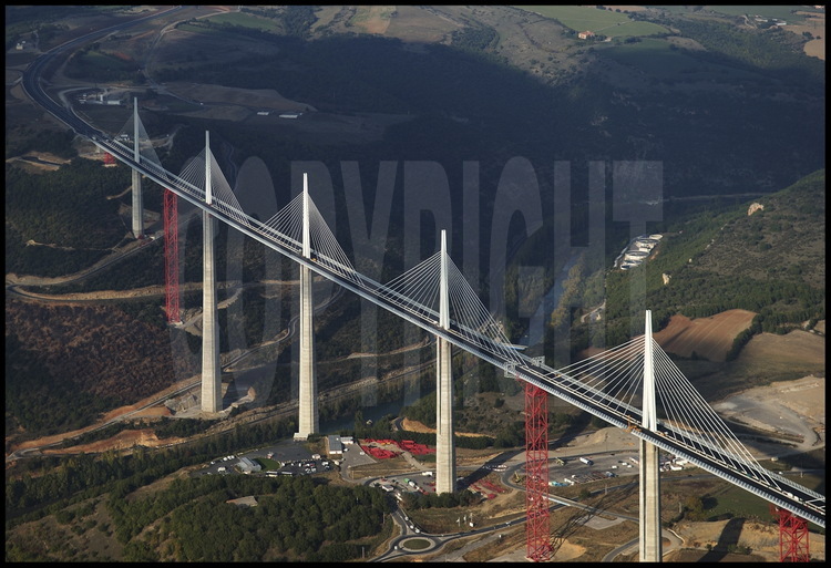 End of October 2004 : building phase is completed. Before the grand opening planned on December 14th, workers are going to take down the temporary structures (in red) and link the roadway to each motorway rim. On the center background, the Causse Rouge.