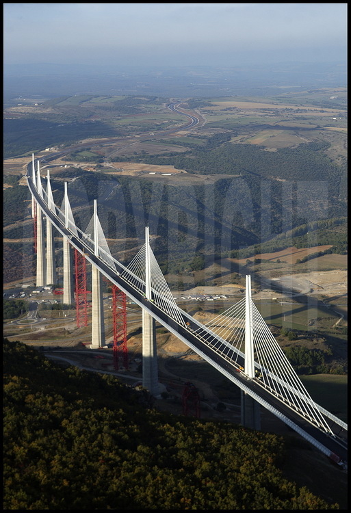 End of October 2004 : building phase is completed. Before the grand opening planned on December 14th, workers are going to take down the temporary structures (in red) and link the roadway to each motorway rim. On the center background, the Causse Rouge.