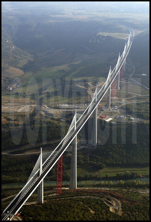 End of October 2004 : building phase is completed. Before the grand opening planned on December 14th, workers are going to take down the temporary structures (in red) and link the roadway to each motorway rim. On the center background, the Causse du Larzac.