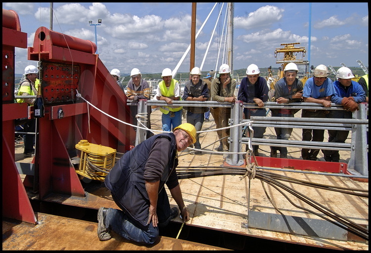 Friday, May 28th, 1PM. Foreman Daniel Feinck, observed by his whole team of welders, measures the space between the two parts of the bridge:  only 40 centimeters until the juncture is completed.