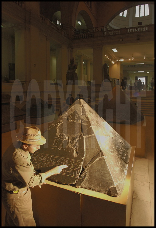 At the Cairo Museum, French archeologist  Vassil Dobrev observes the pyramidion (the stone that crowns the top of a pyramid) from the pyramid of King Khendjer. This 13th dynasty pharaoh from the Middle Kingdom had his pyramid built at the far southern end of the Saqqara site. Khendjer, or “son of Re”, also had another name: Userkare, meaning “King of Lower Egypt”. According to Vassil Dobrev, who indicates the latter’s cartouche on the pyramidion, the second name is a reference to Khendjer’s ancestor Userkare, second king of the VIth dynasty who ruled for a mere 2 years from 2323 to 2321 BCE (Old Kingdom).