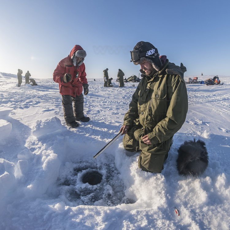 Canada - Etat du Nunavut - Opération Nunalivut 2018 - Environs de Cambridge Bay -  Camp de survie n° 1 : les militaires sont initiés par les rangers à la pêche sous glace, laquelle peut sauver des vies en cas d'isolement en région polaire. Ici, le ranger Allan Elatiak (à gauche) explique au master caporal Luke Johnston, 27 ans, le mouvement à adopter pour ferrer le poisson. // Canada - State of Nunavut - Operation NUNALIVUT 2018 - Surroundings of Cambridge Bay - Survival Camp # 1: Soldiers are initiated by the Rangers into ice fishing, which can save lives in polar isolation. Here, ranger Allan Elatiak (left) explains to Master Corporal Luke Johnston, 27, the move to adopt to hook the fish.