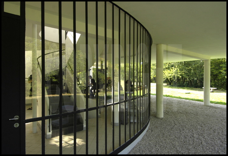 Au rez-de-chaussée, l’entrée ainsi que l’accès à l’étage et aux terrasses. Située au milieu d'une pelouse entourée de prairies et de vergers dominant la vallée de la Seine, la villa Savoye est la parfaite illustration de la théorie des cinq points de l'architecture moderne formulée par son créateur, l’architecte suisse Charles-Édouard Jeanneret-Gris, dit Le Corbusier en 1927, pour théoriser les principes fondamentaux du Mouvement moderne : les pilotis, les toits-jardins, le plan libre, la fenêtre en longueur et la façade libre. Achevé en 1931, la villa est classée monument historique en 1965, du vivant de l'architecte. Elle fut ensuite restaurée jusqu'en 1997, après des années d'abandon et est désormais ouverte au public.